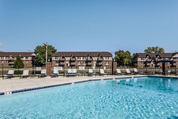 A lakeside pool with lounge chairs and apartments in the background